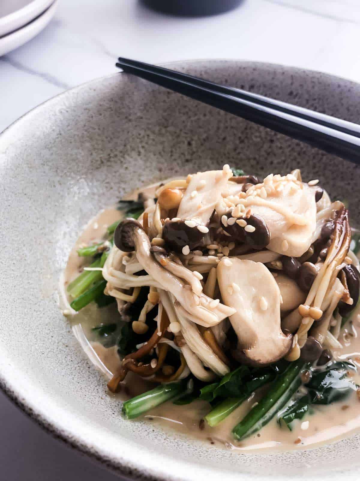 Marinated Japanese Mushroom Salad with Sesame Spinach in a white bowl with a pair of black chopsticks