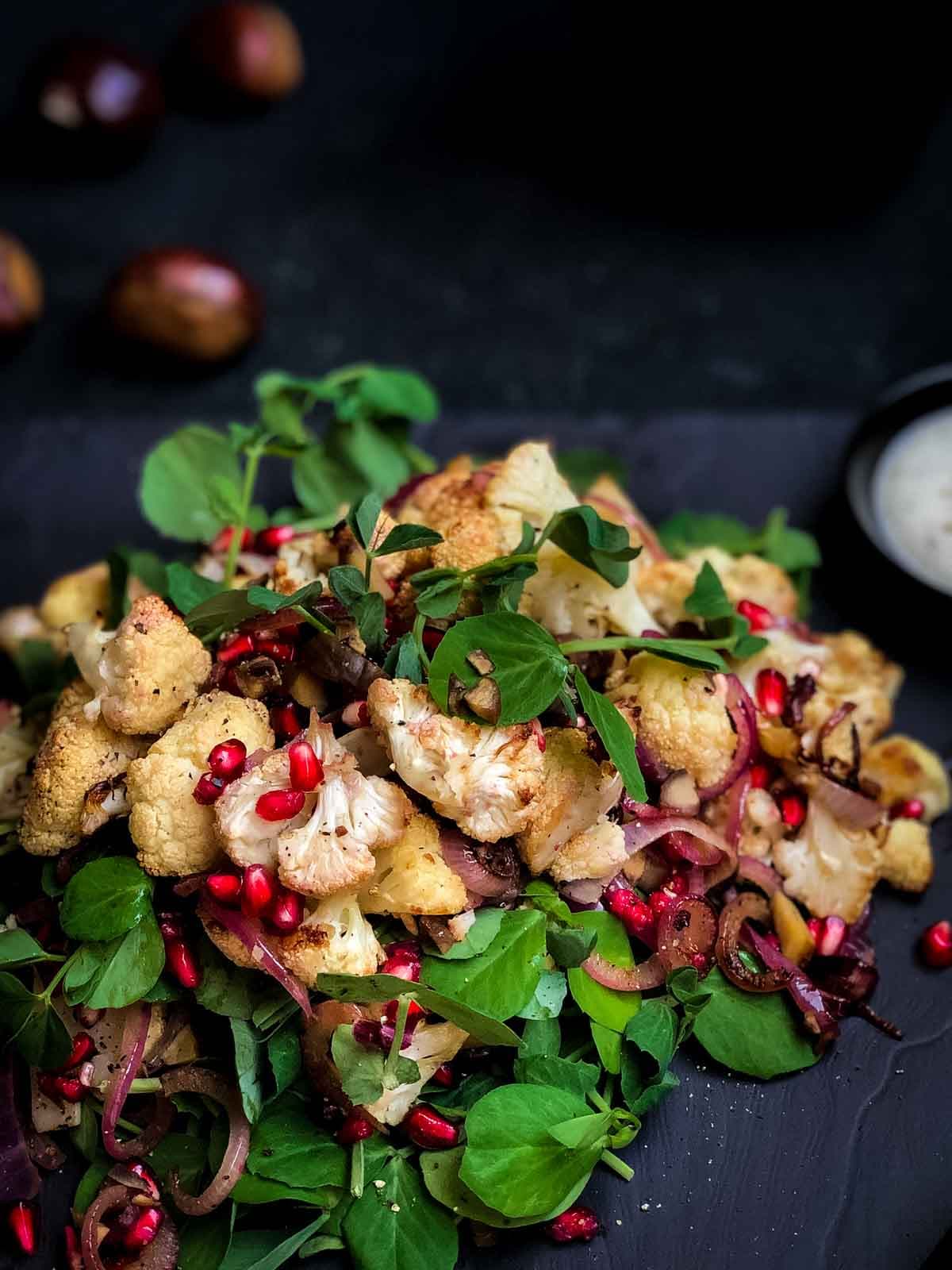 Roasted Cauliflower Salad with Chestnuts and Pomegranate on a black slate