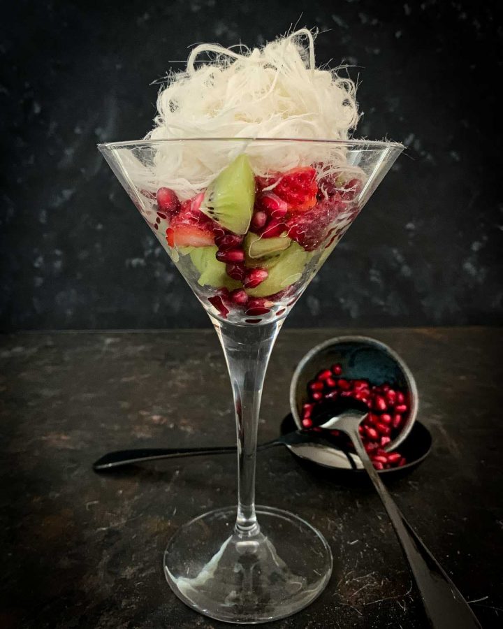 Red and Green Fruit Salad with Vanilla Persian Fairy Floss in a martini glass served with pomegranate arils on the side