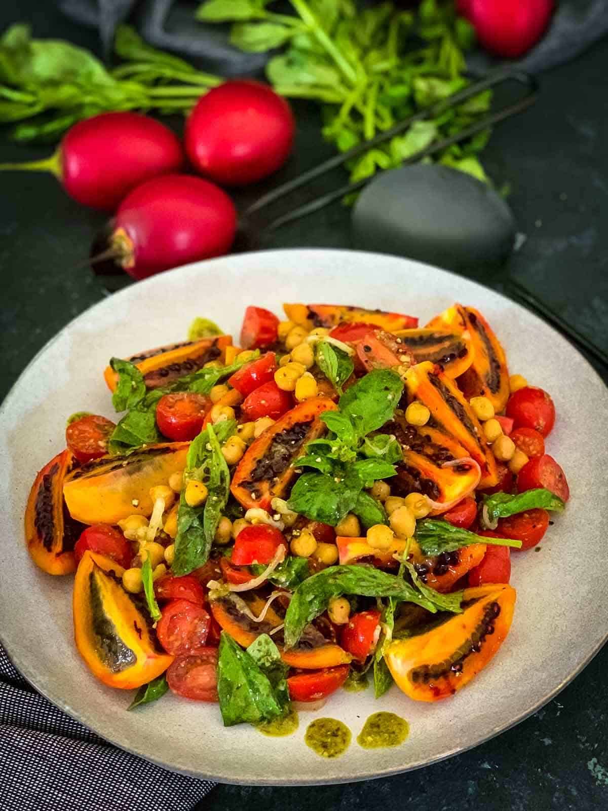 Red Tamarillo Salad with Basil on a white plate with whole red tamarillos on the side