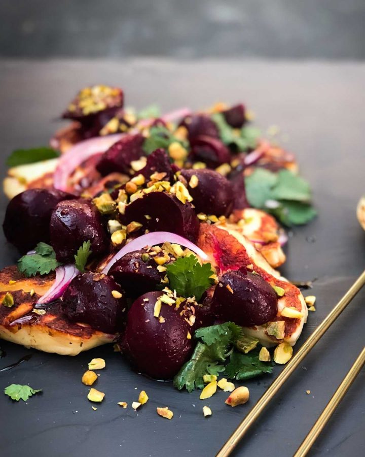 Roasted Beetroot Salad with Halloumi and Pomegranate Glaze on a slate board with gold salad server