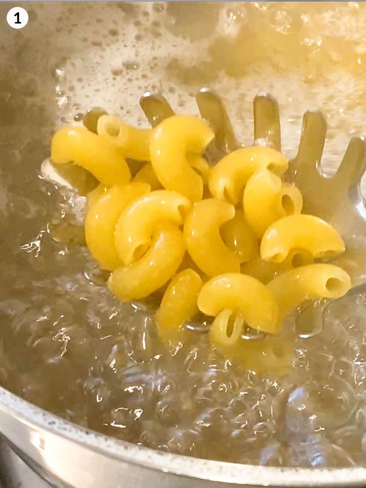 ladle scooping macaroni pasta from boiling water