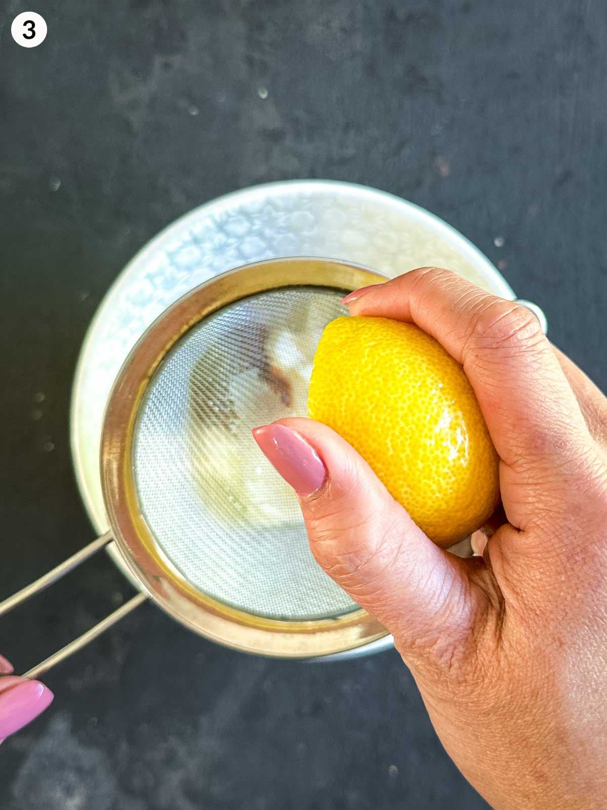 Squeezing lemon juice through a sieve into a bowl