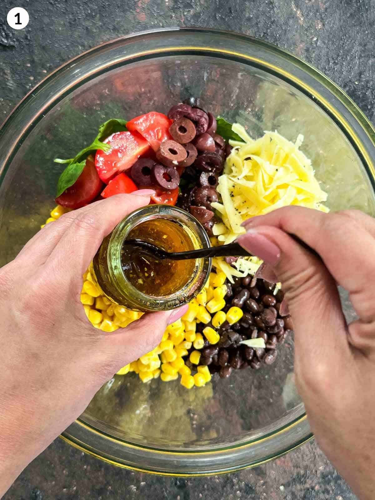 Pouring Santa Fe salad dressing into a mixing bowl of Santa Fe salad ingredients