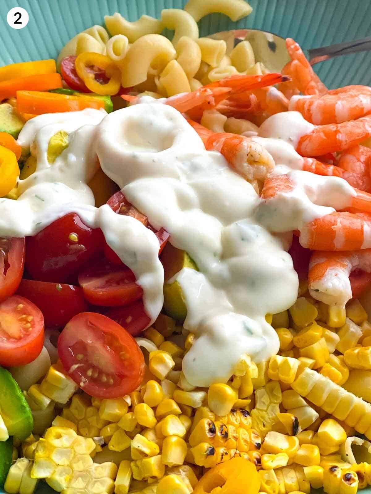 macaroni salad ingredients with dressing on top ina big bowl