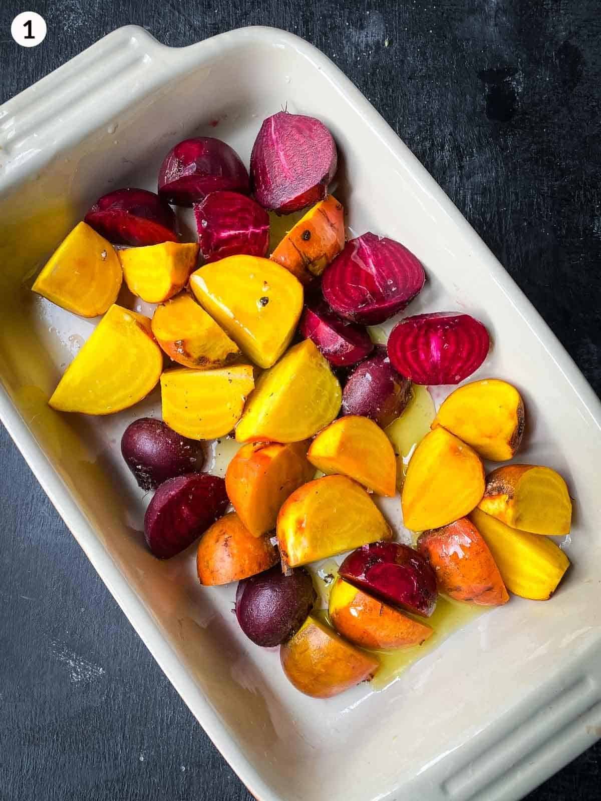 cut baby beets covered in olive oil in a large baking dish