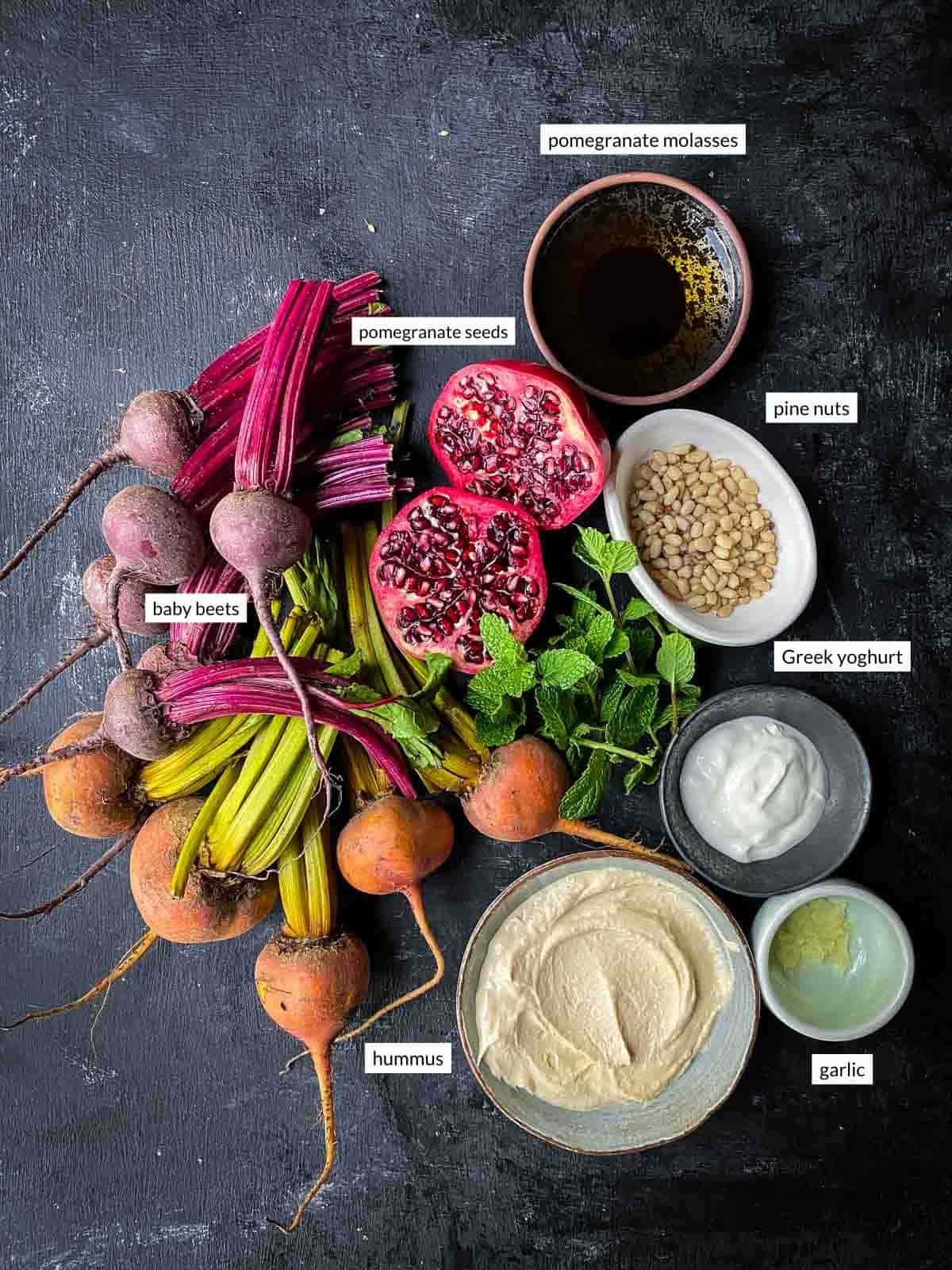 labelled ingredients photo showing baby beets, next to pomegranate, pomegranate molasses, pine nut, yoghurt, garlic and hummus.