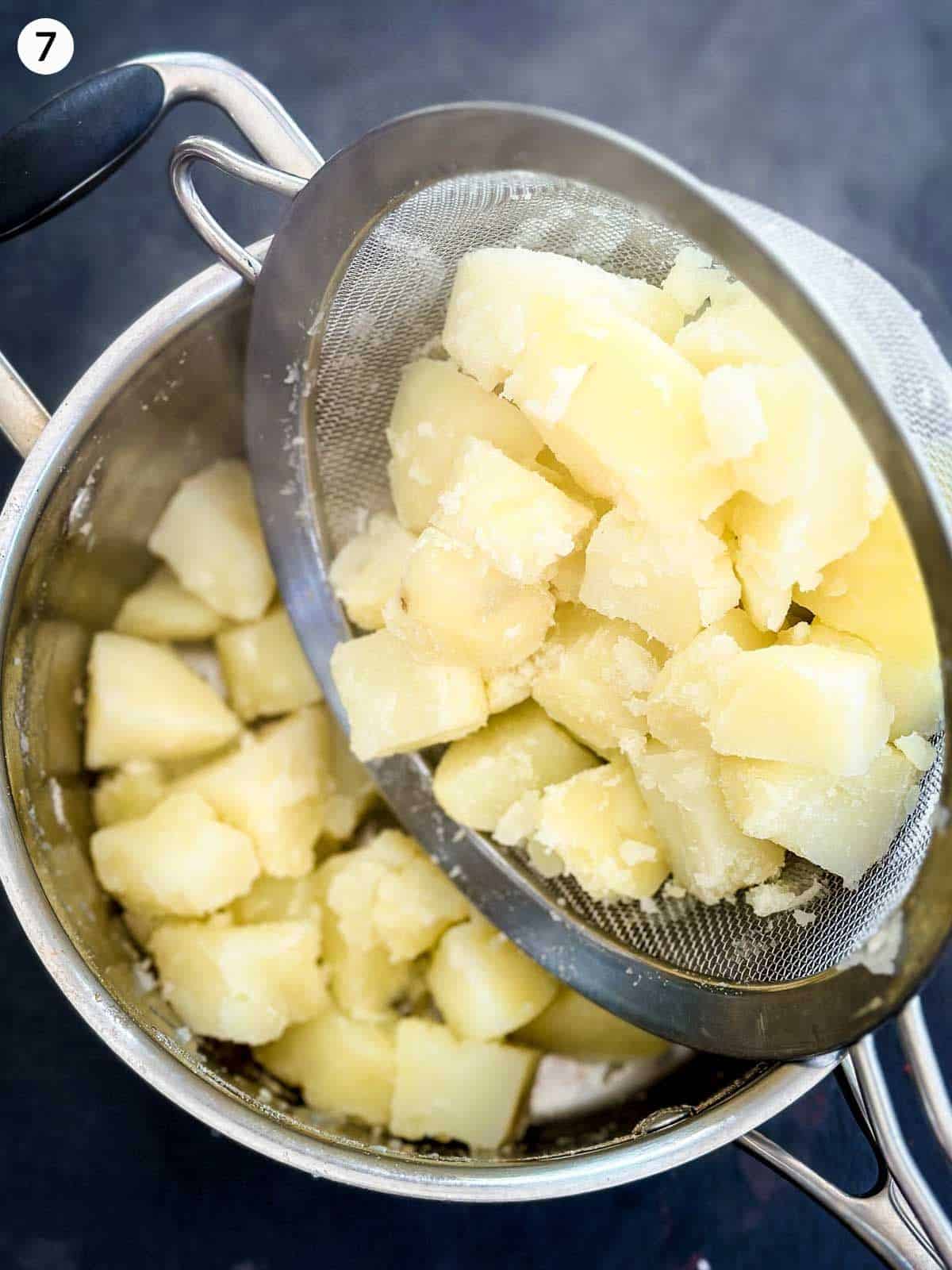 Pouring cooked potatoes in a sieve into a pot