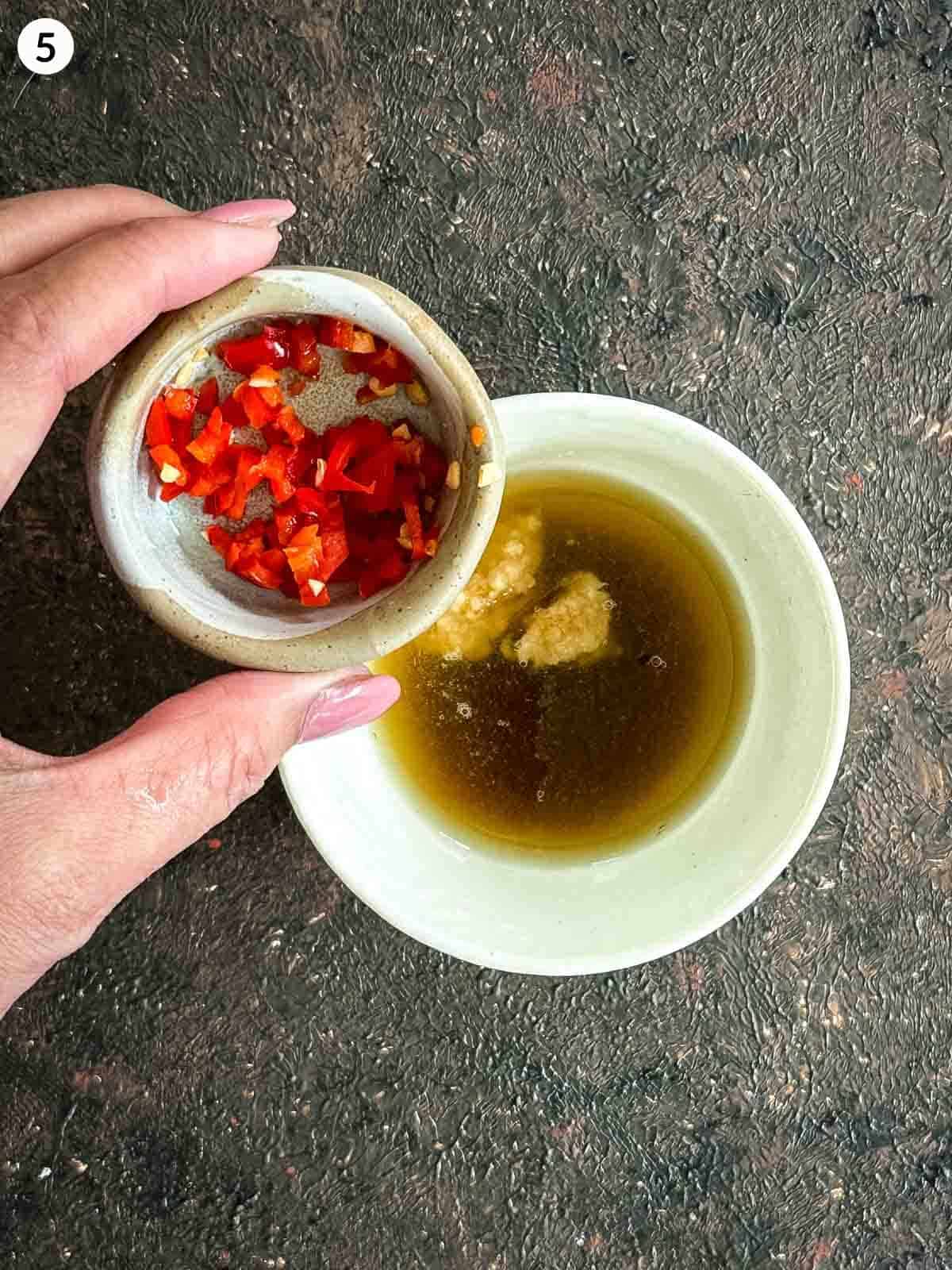 Adding cut chilli into a bowl of fish sauce salad dressing