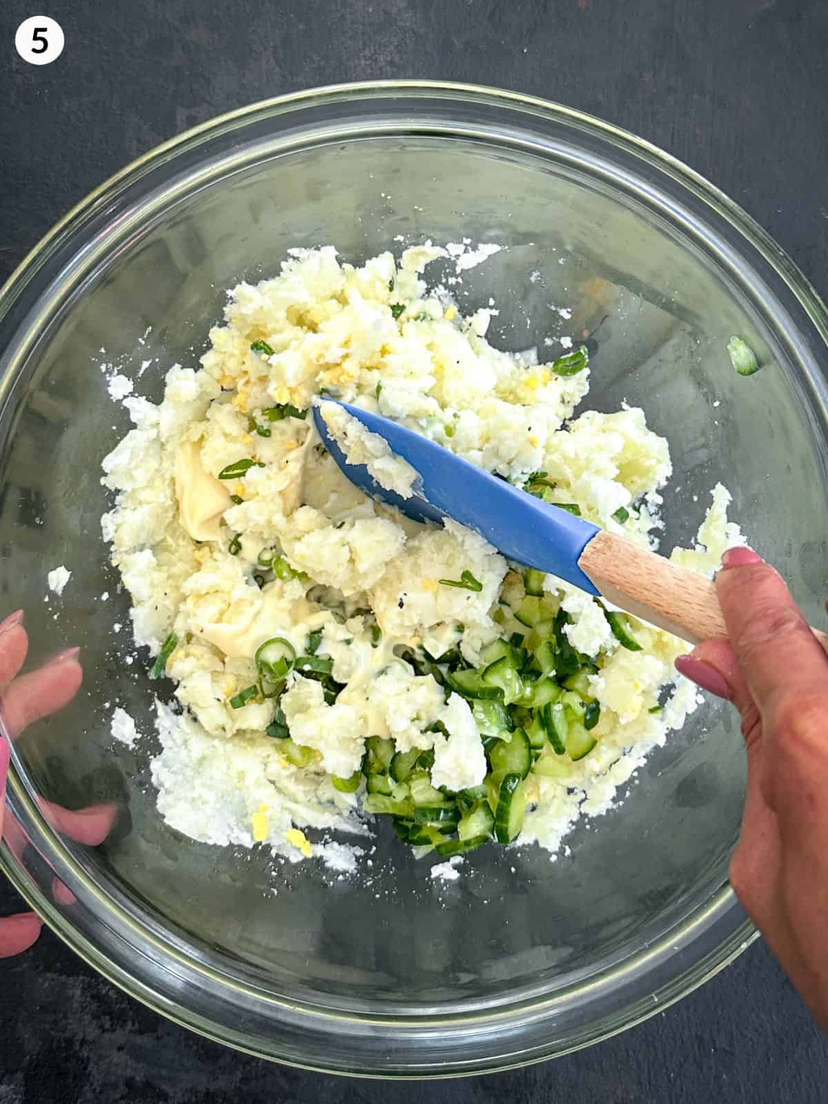 Mixing Korean potato salad ingredients in a glass bowl