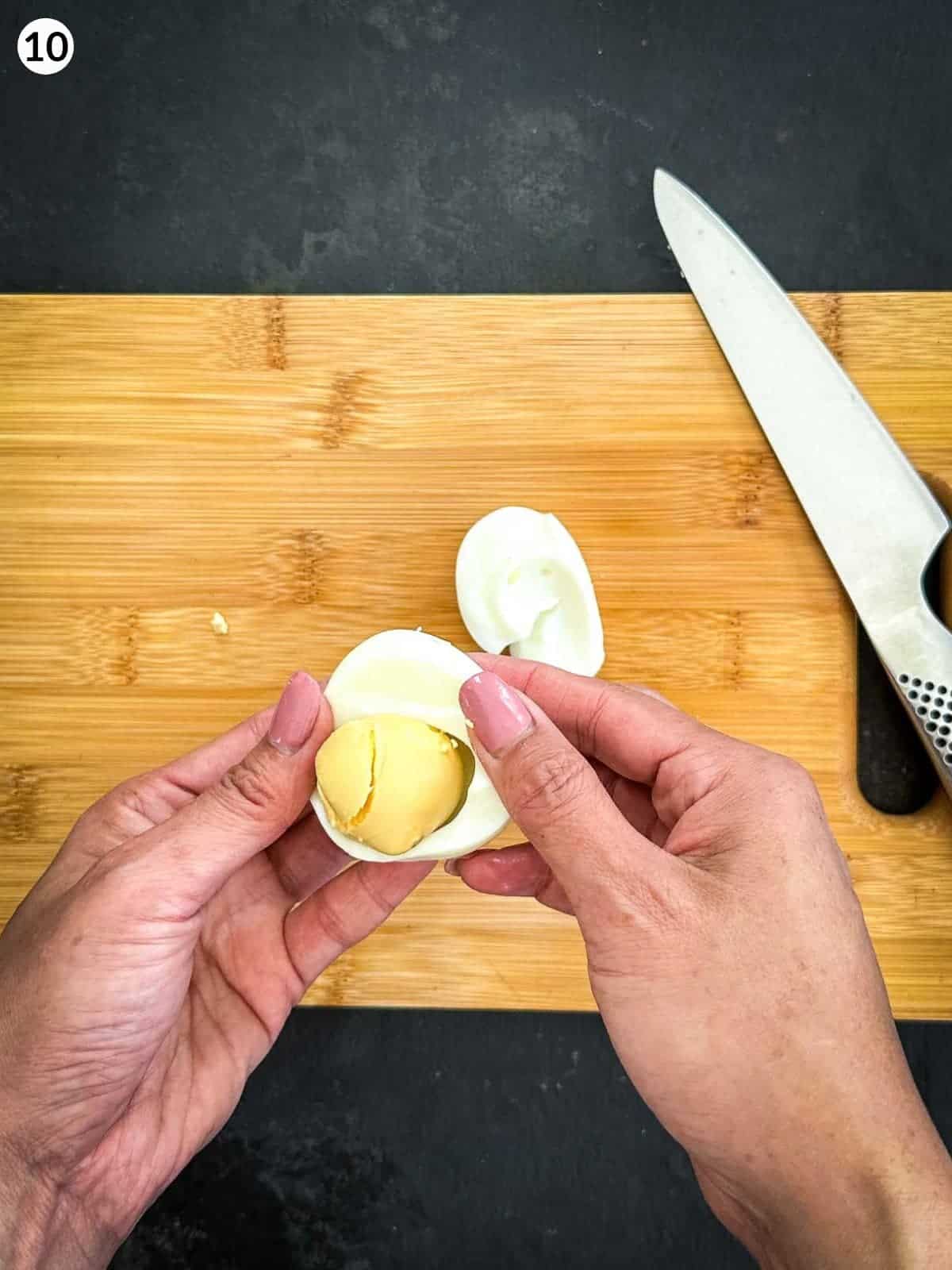 Removing egg yolk from the egg white over a wooden chopping board