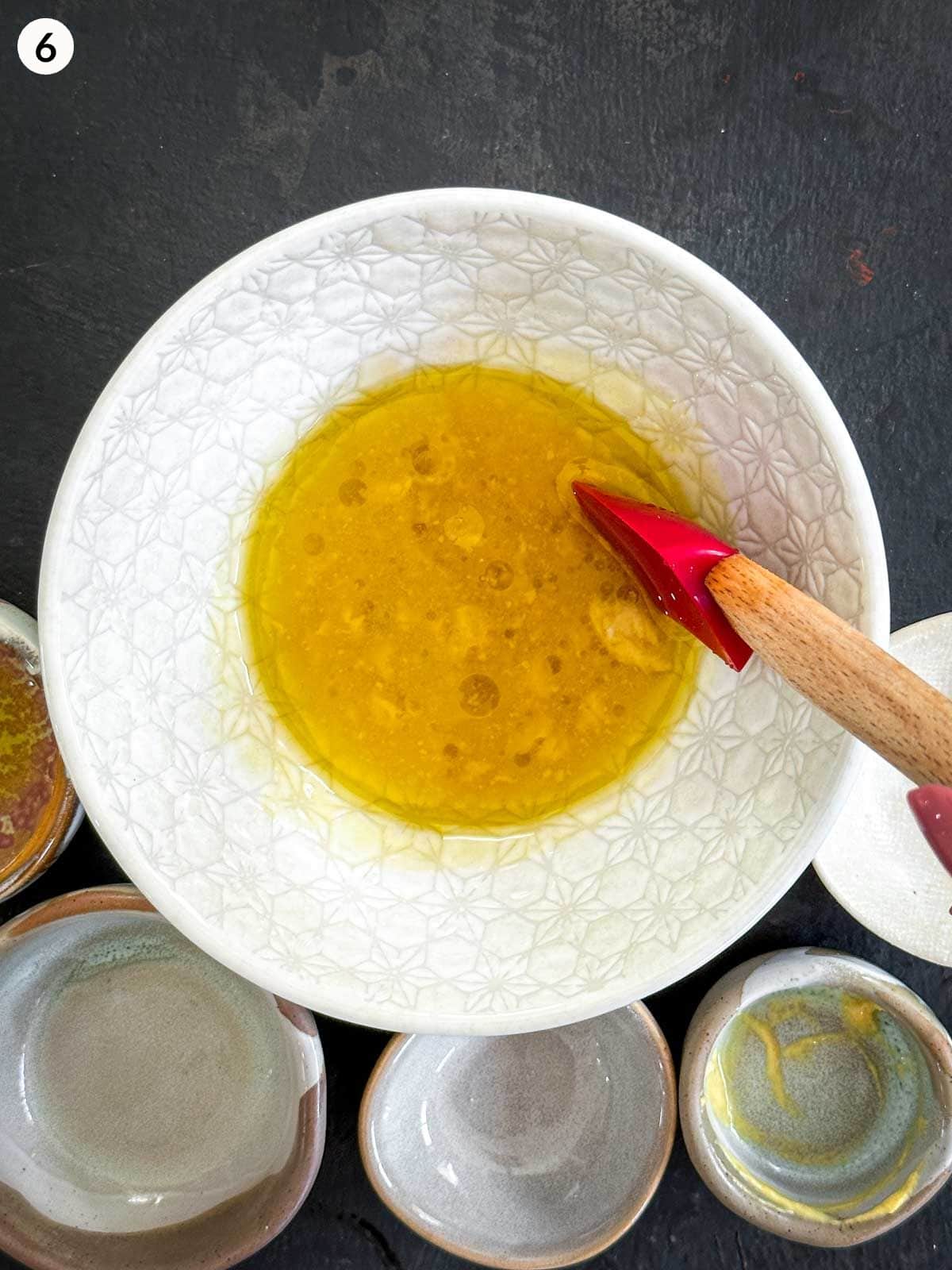 Mixing a bowl of Dijon mustard dressing with a red spatula
