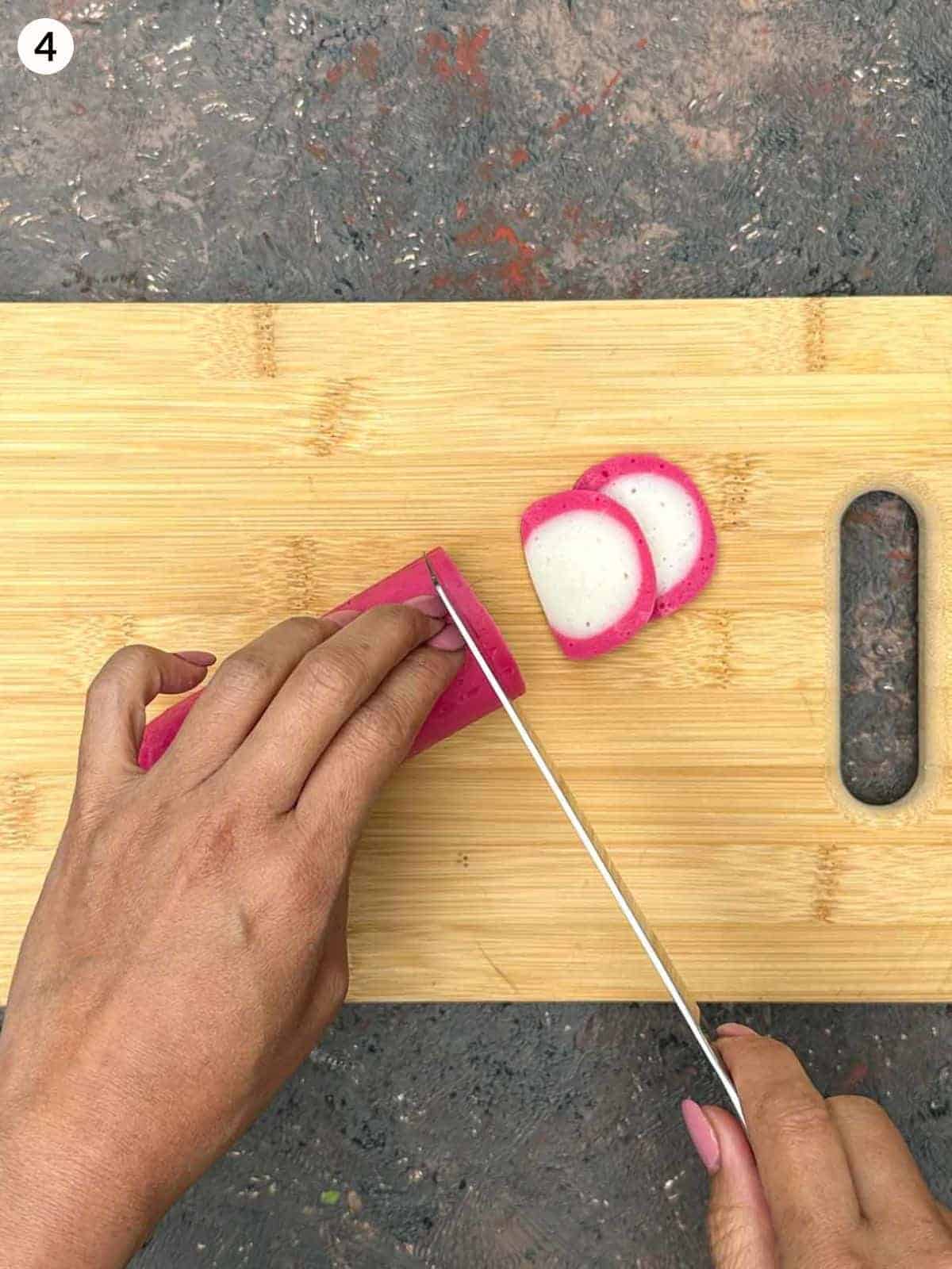 Slicing kamaboko with a knife on a wooden board