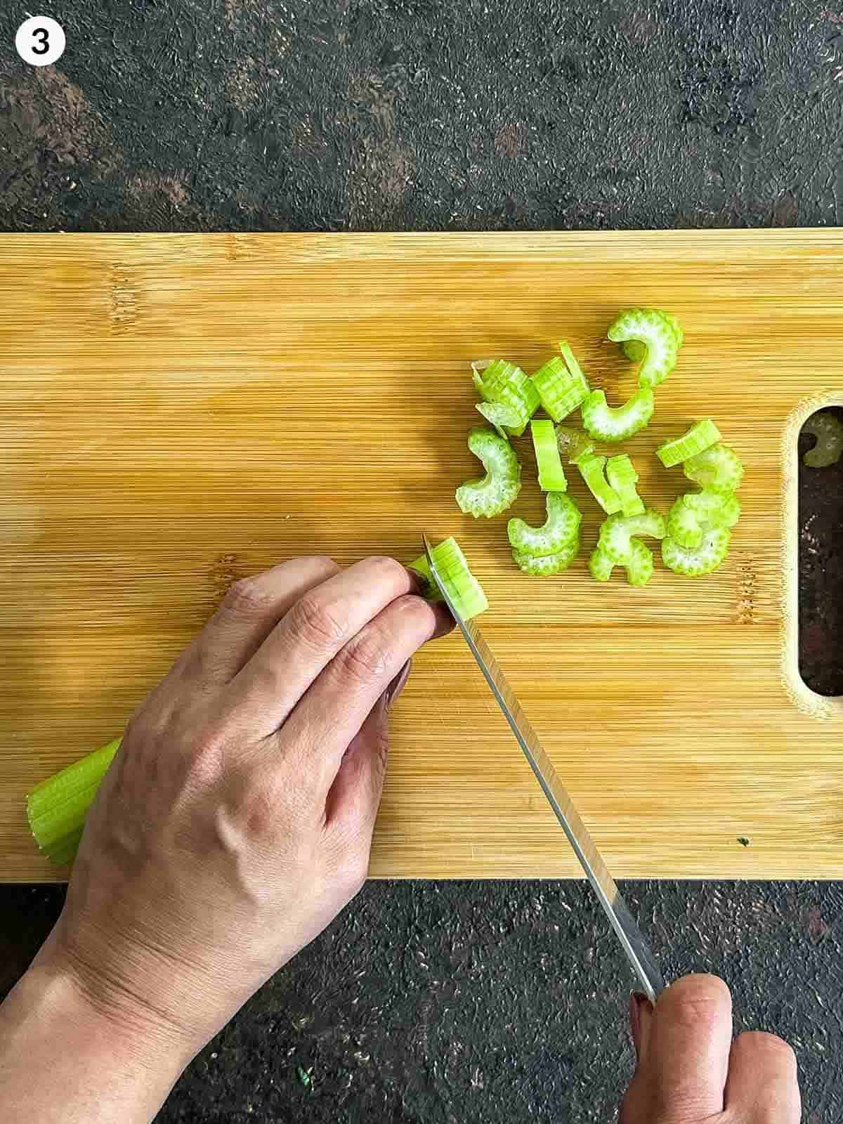 Chopping celery on a wooden board with a knife