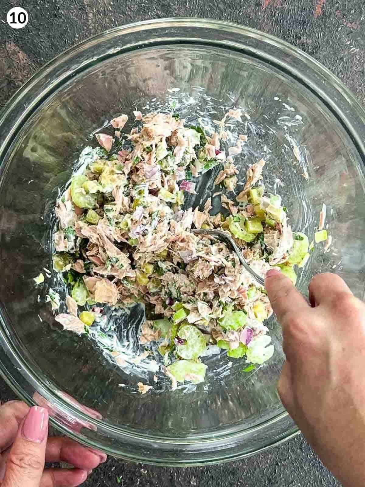 Mixing a glass bowl of healthy tuna salad ingredients