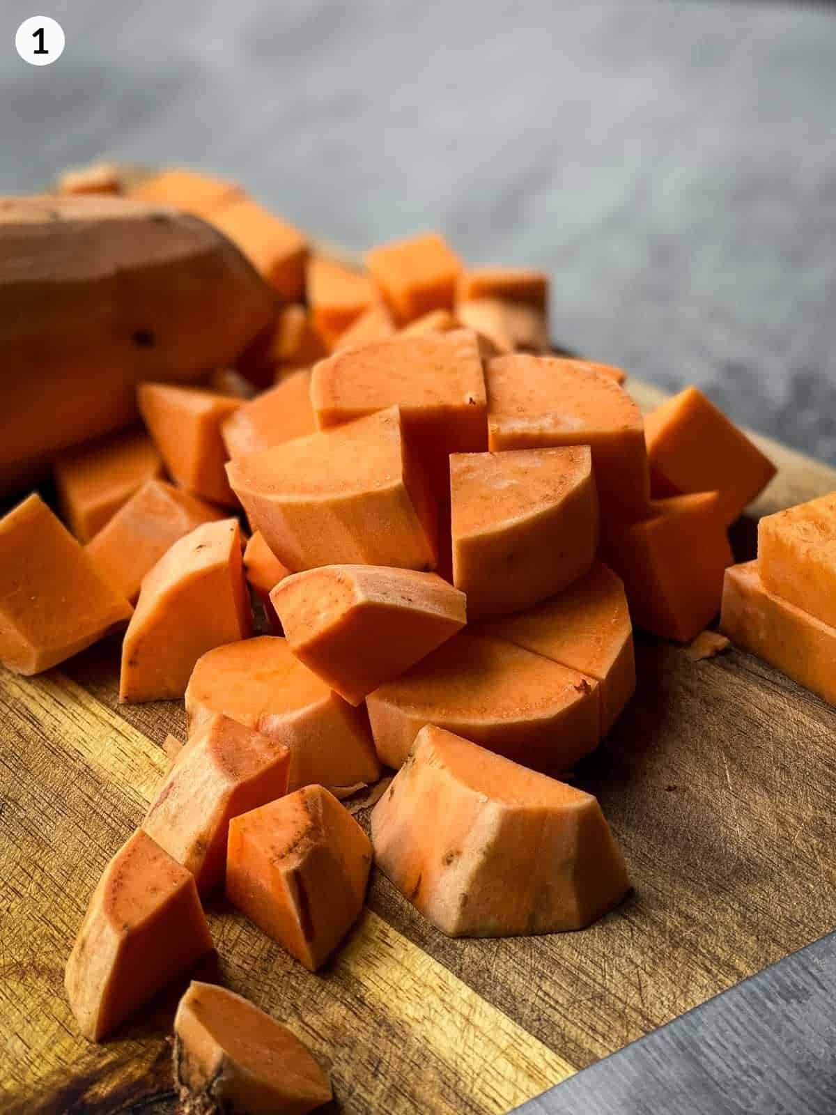 cubes of uncooked sweet potato on a wooden chopping board