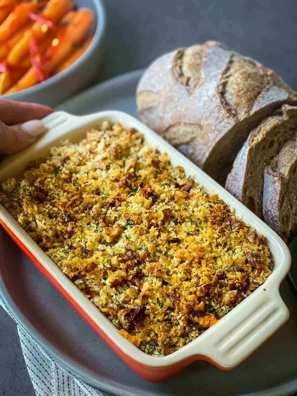 Savoury Sweet Potato Casserole in a ceramic baking dish, with bread on the side