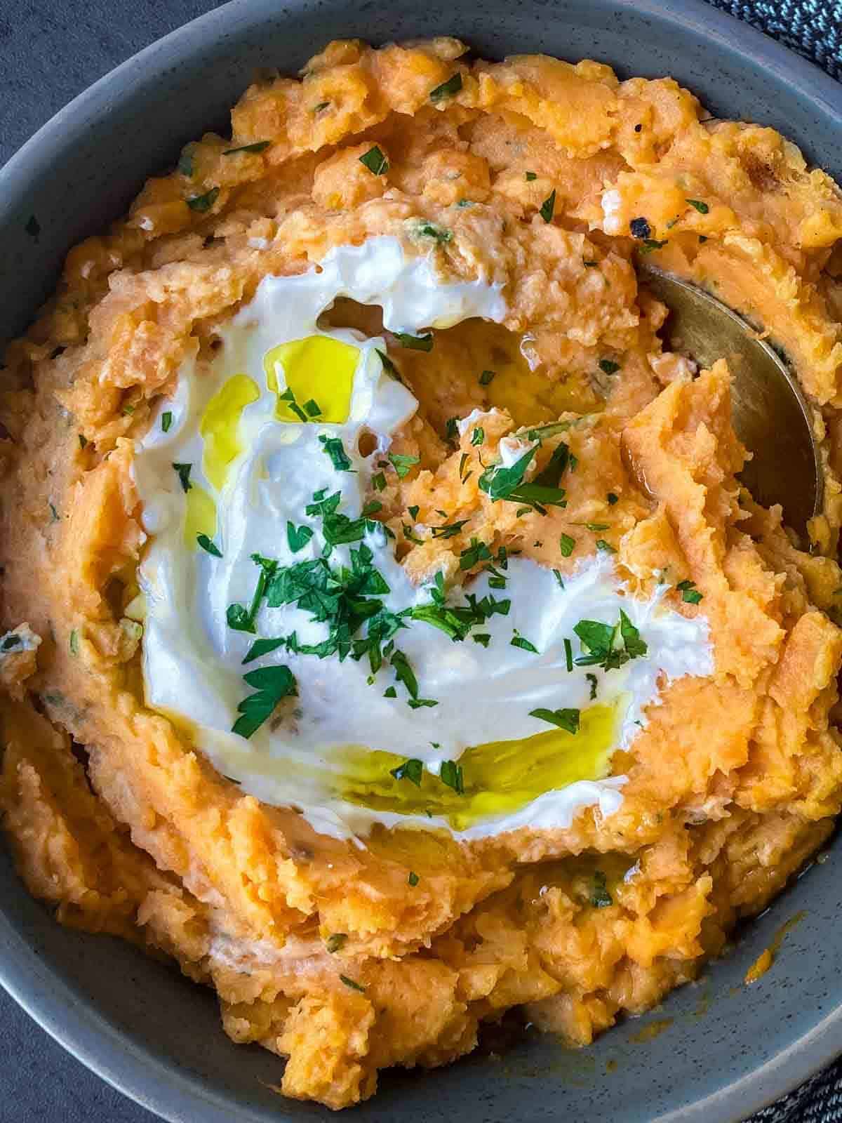 mashed sweet potato in a grey bowl with a serving spoon