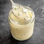 Lifting a serve of Creme Fraiche and Chives Dressing from a jar