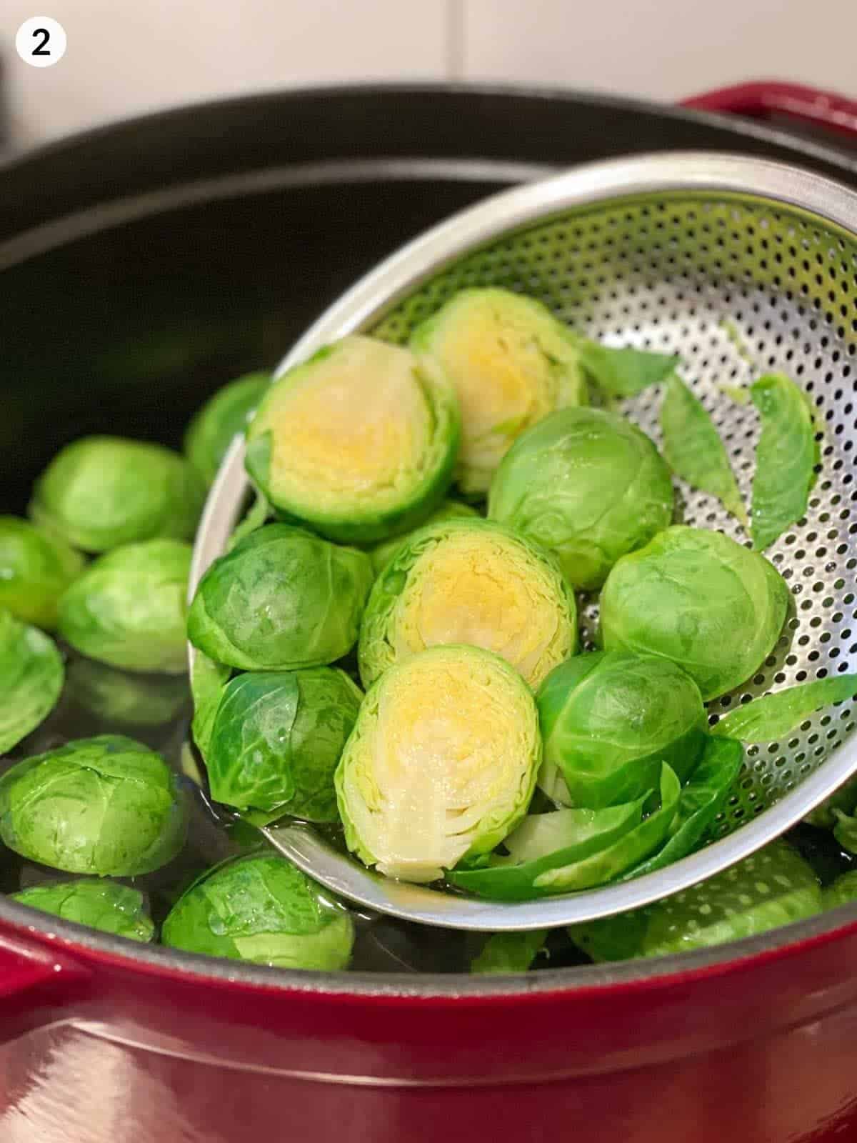boiling Brussels sprouts in a colander in a red pot