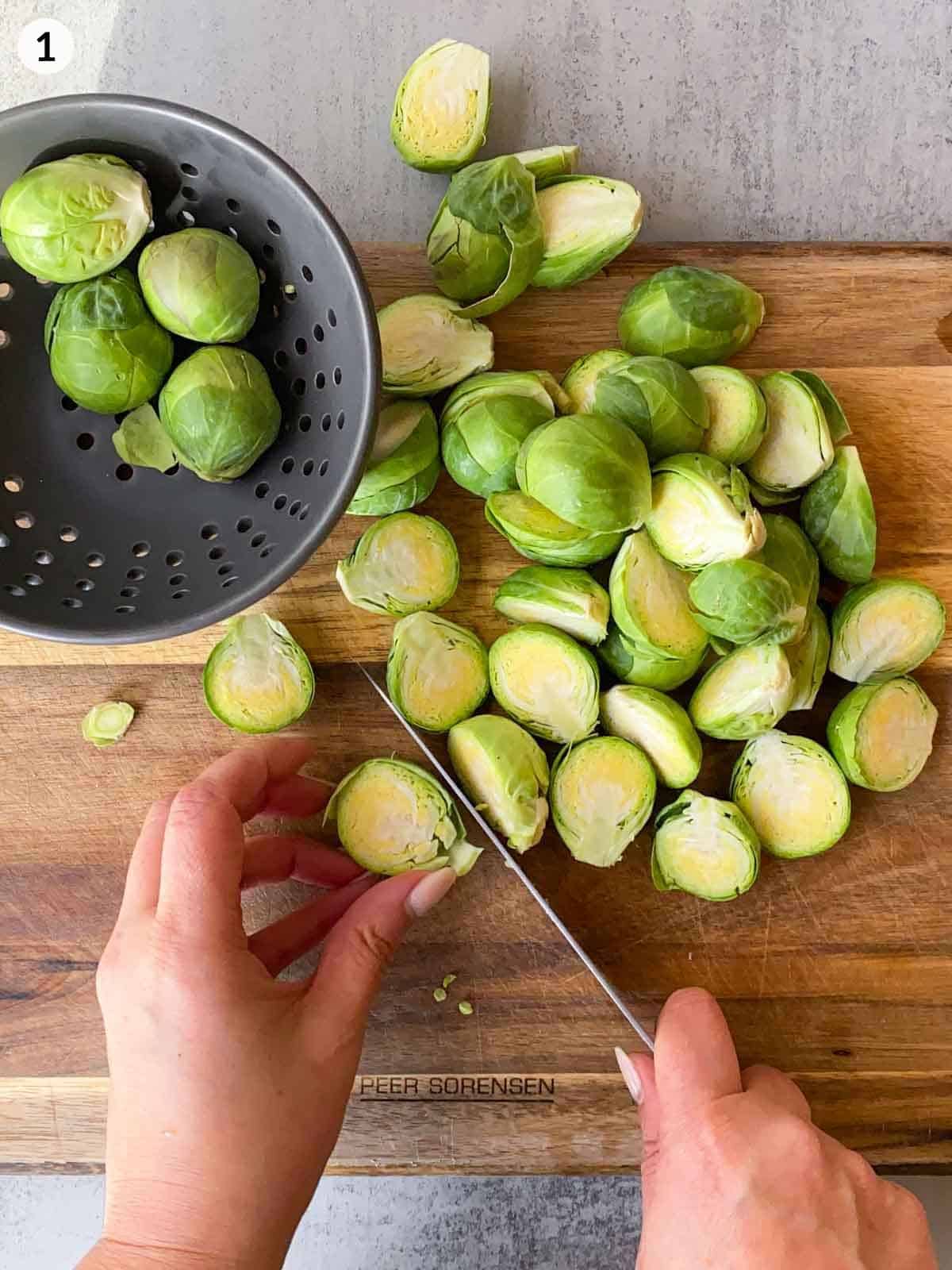 Cutting Brussels sprouts in half on a wooden chopping board with a knife