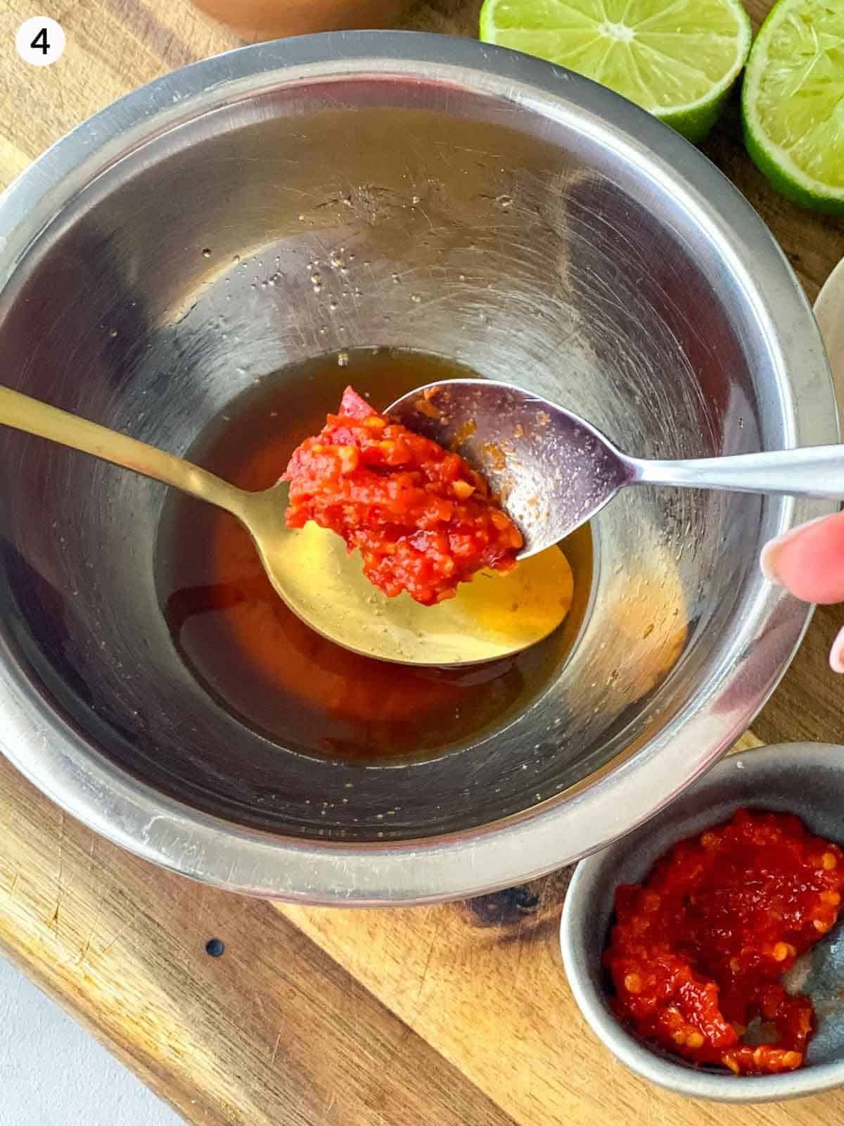 Adding a teaspoon of chilli paste into a mixing bowl of fish sauce