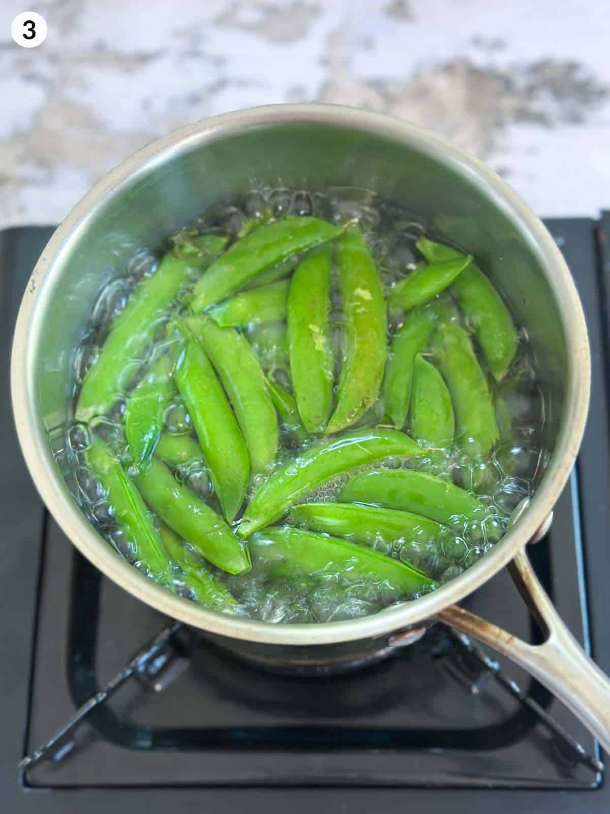 Boiling fresh peas in a saucepan