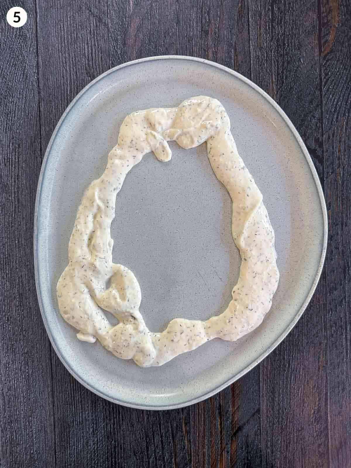 Adding tzatziki in a circle on a plate
