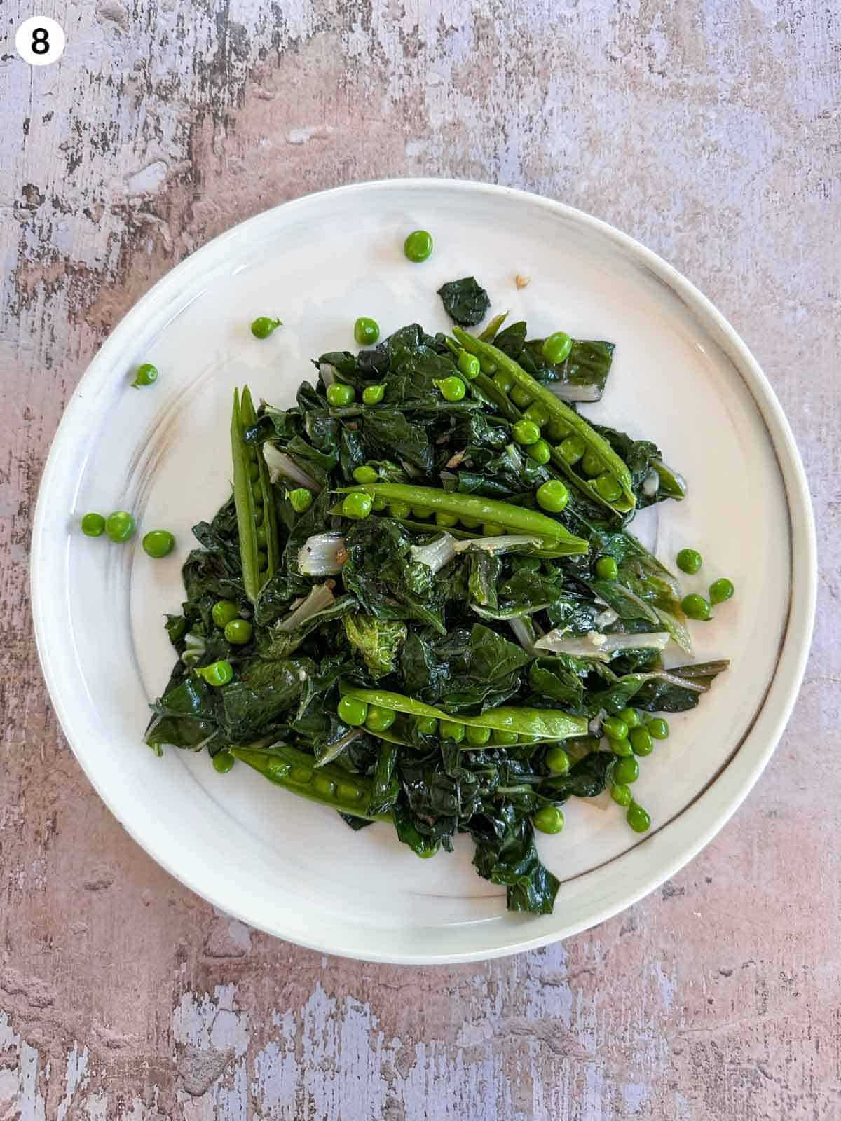 sauteed silverbeet and peas in the pod on a white plate