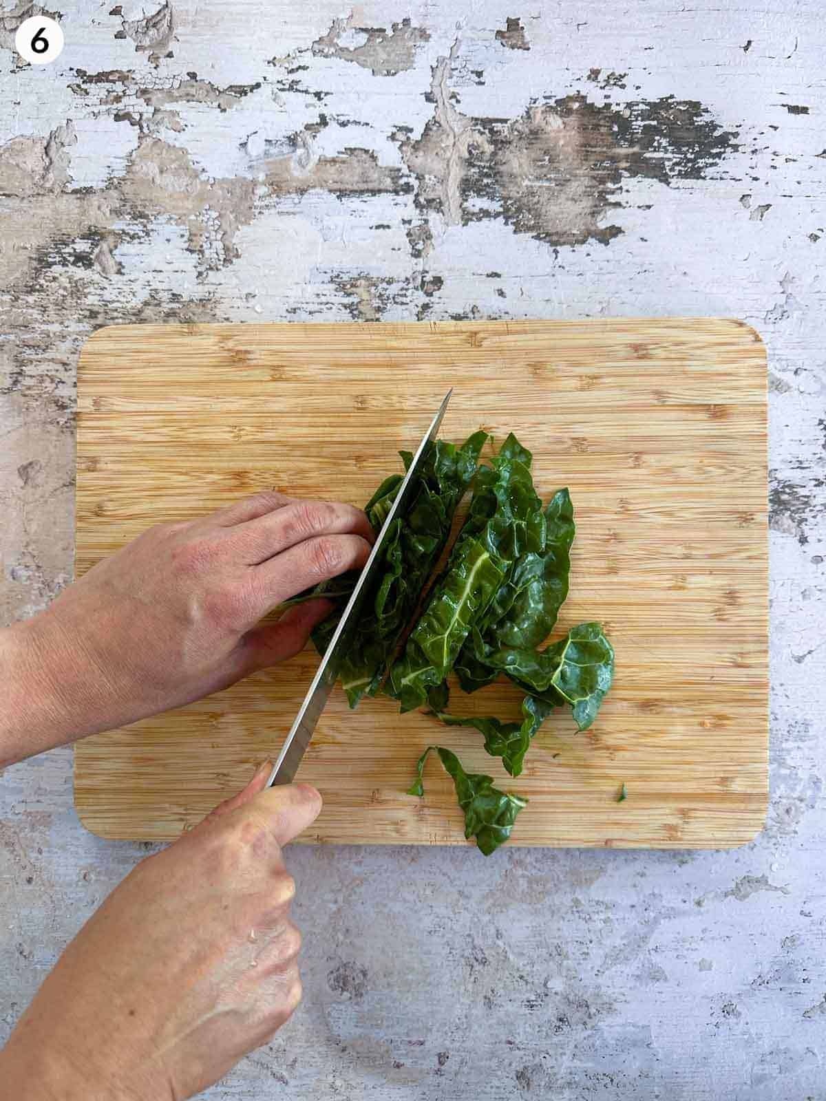 Chopping silverbeet with a knife on a wooden chopping board