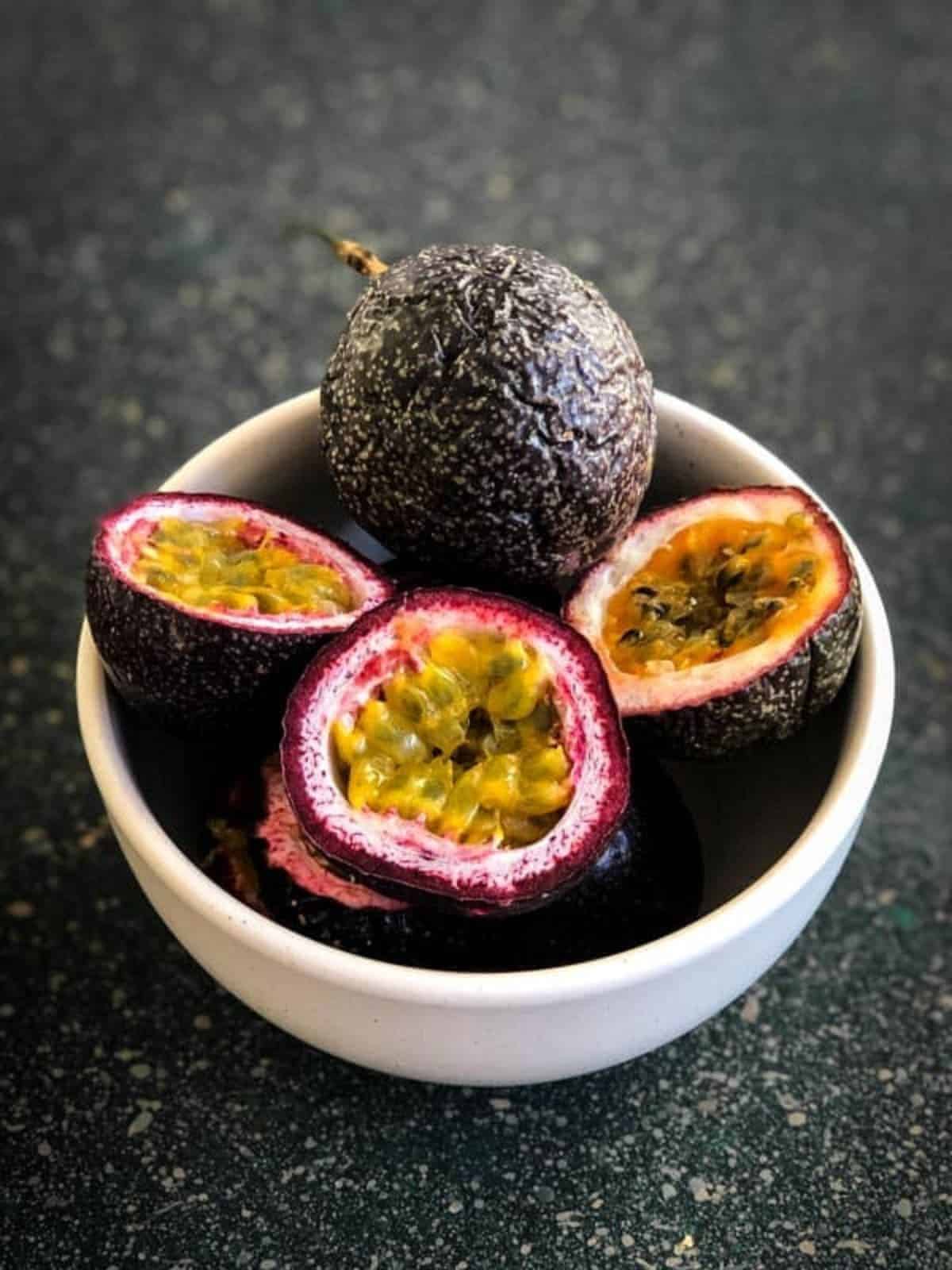 Halved passionfruit in a white bowl